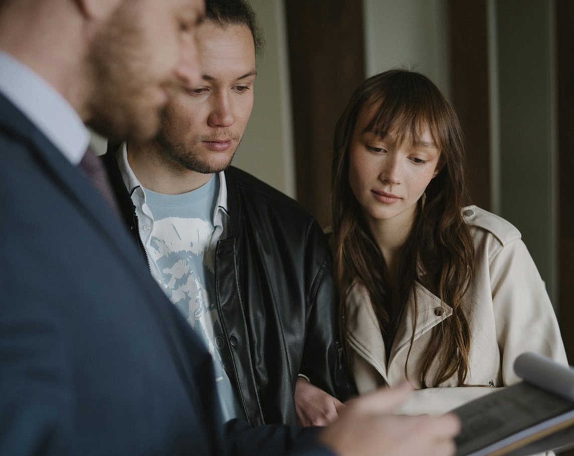 Doradca nieruchomości przedstawiający parze klientów ofertę